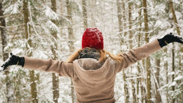 Woman with outstretched arms in a wooded winter environment