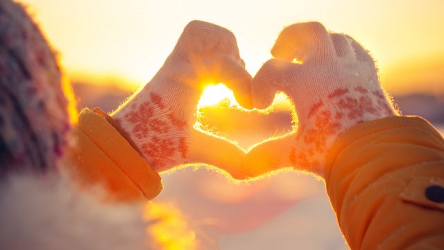 A woman wearing gloves making a heart symbol