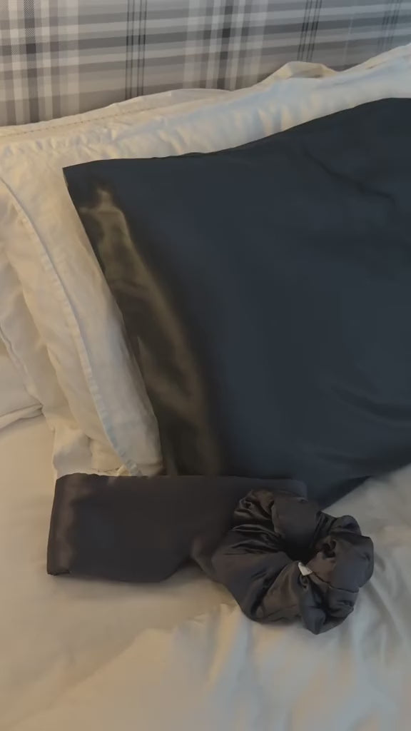 Charcoal grey silk eye mask and pillowcase being used by a woman showing her luxury nighttime routine